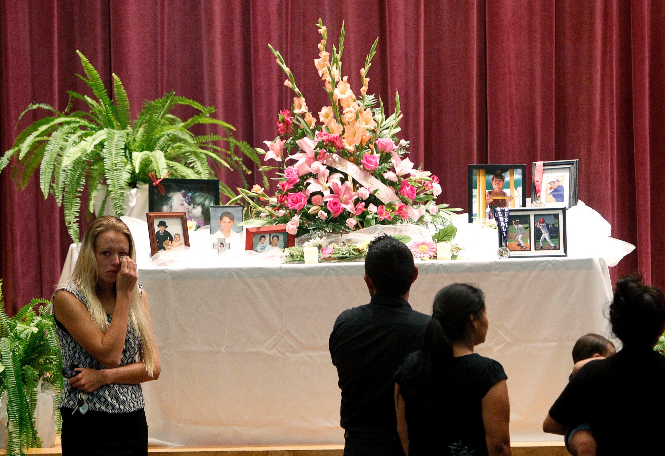 PHOTO: Mourners look at a display of photos during a memorial service at Bell High School for the victims of Thursday's shootings on Sunday, Sept. 21, 2014 in Bell, Fla.