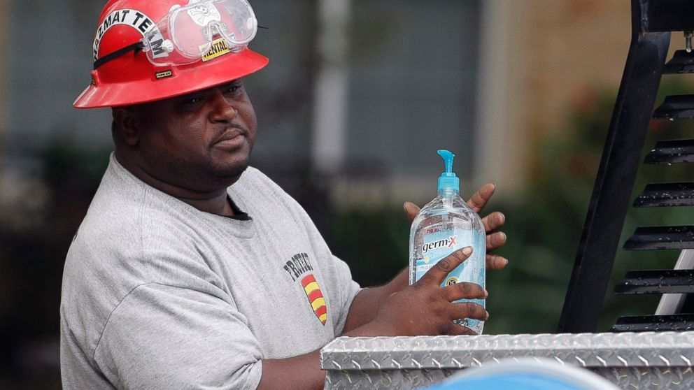 PHOTO: A Protect Environmental Services employee sanitizes his hands outside the apartment of a healthcare worker who tested positive for Ebola, Oct. 13, 2014, in Dallas.