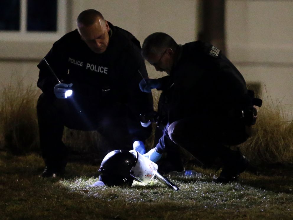 PHOTO: Police shine a light on a helmet as they investigate the scene where two police officers were shot outside the Ferguson Police Department, March 12, 2015, in Ferguson, Mo.