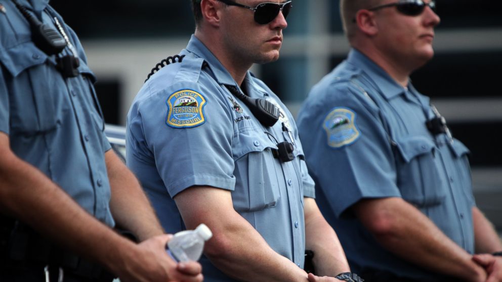 Police officers wear what appear to be body cameras as they hold the line against protesters gathered at the police station during a rally in Ferguson, Mo. on Aug. 30, 2014.