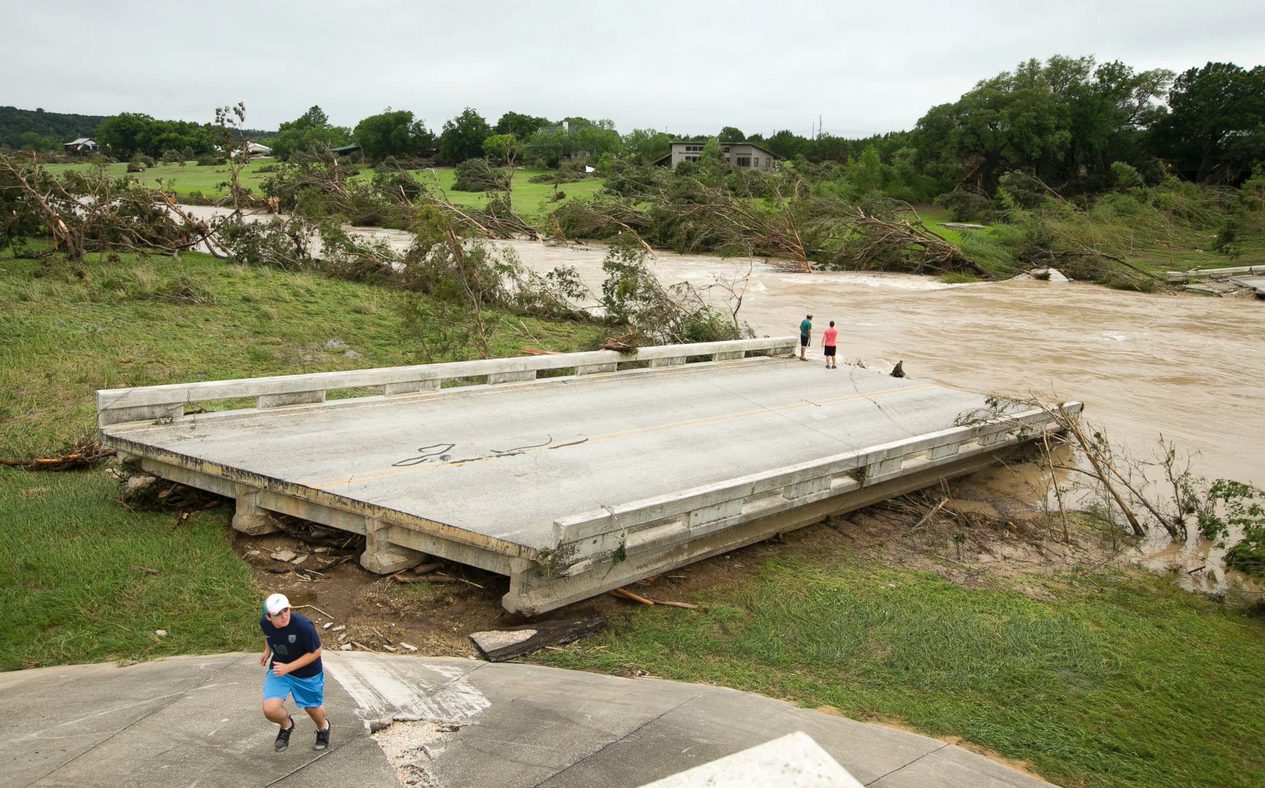 PHOTO: Dustin McClintock, of Wimberley,, Brandon Bankston, of Blanco, Hesston Krause, of Smithson Valley, look at the Fischer Store Road bridge over the Blanco River near Wimberley, Texas, which was destroyed in a flood on Sunday May 24, 2015.