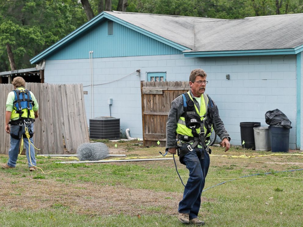 PHOTO: Engineers in safety equipment cross in front of a home where a sinkhole opened up underneath a bedroom and swallowed Jeffrey Bush, in Seffner, Fla., March 2, 2013.