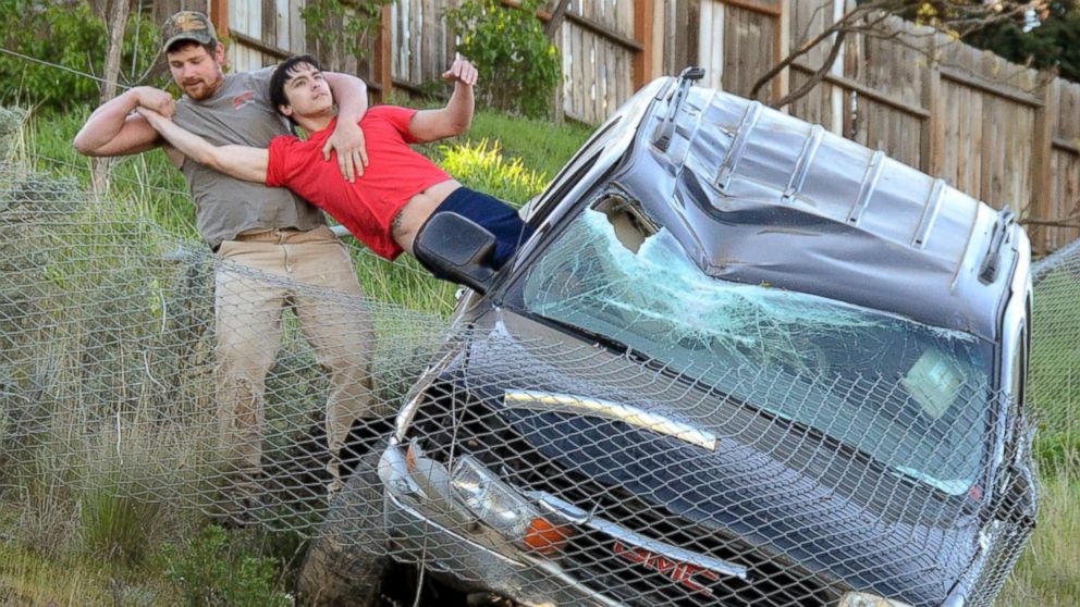 An unidentified passer-by pulls the driver from a SUV to safety after the vehicle traveled downhill and was stopped by a chain link fence just short of a 30-foot vertical drop onto the Bryden Canyon Road, April 15, 2015, in Lewiston, Idaho.
