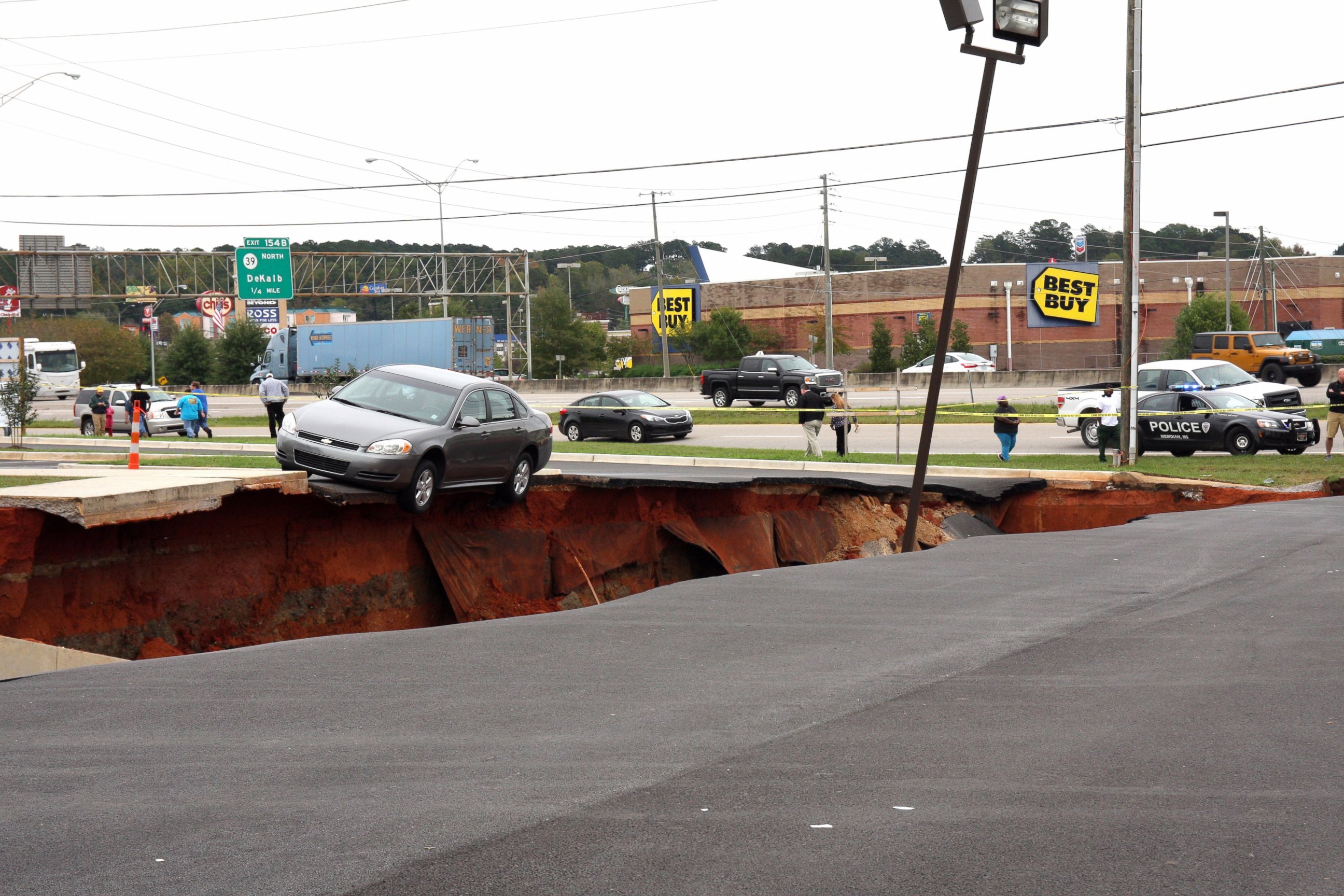 PHOTO: A car teeters on the edge of a cave-in of a parking lot in Meridian, Miss., Sunday, Nov. 8, 2015.