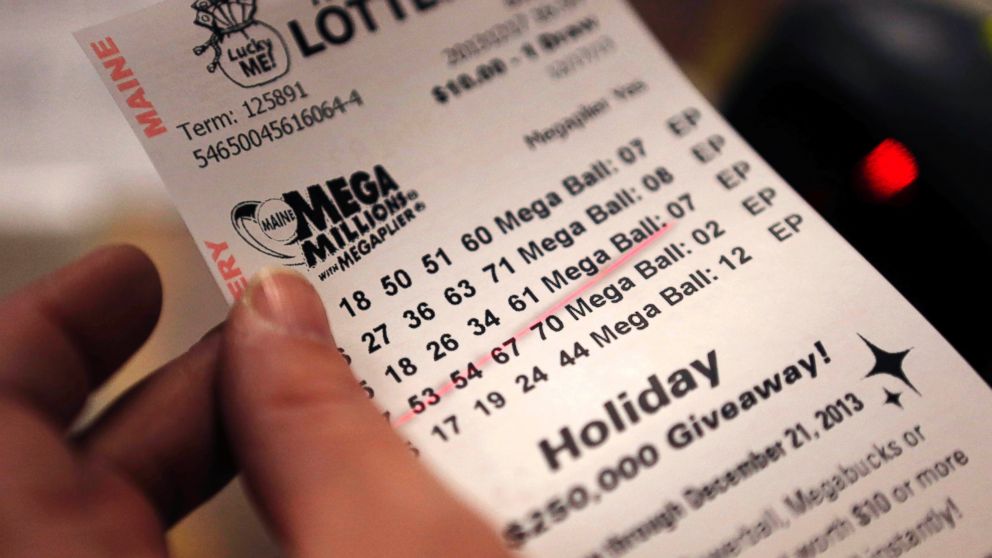 A cashier holds a Mega Millions lottery ticket at a convenience store in Lisbon, Maine, Tuesday, Dec. 17, 2013.