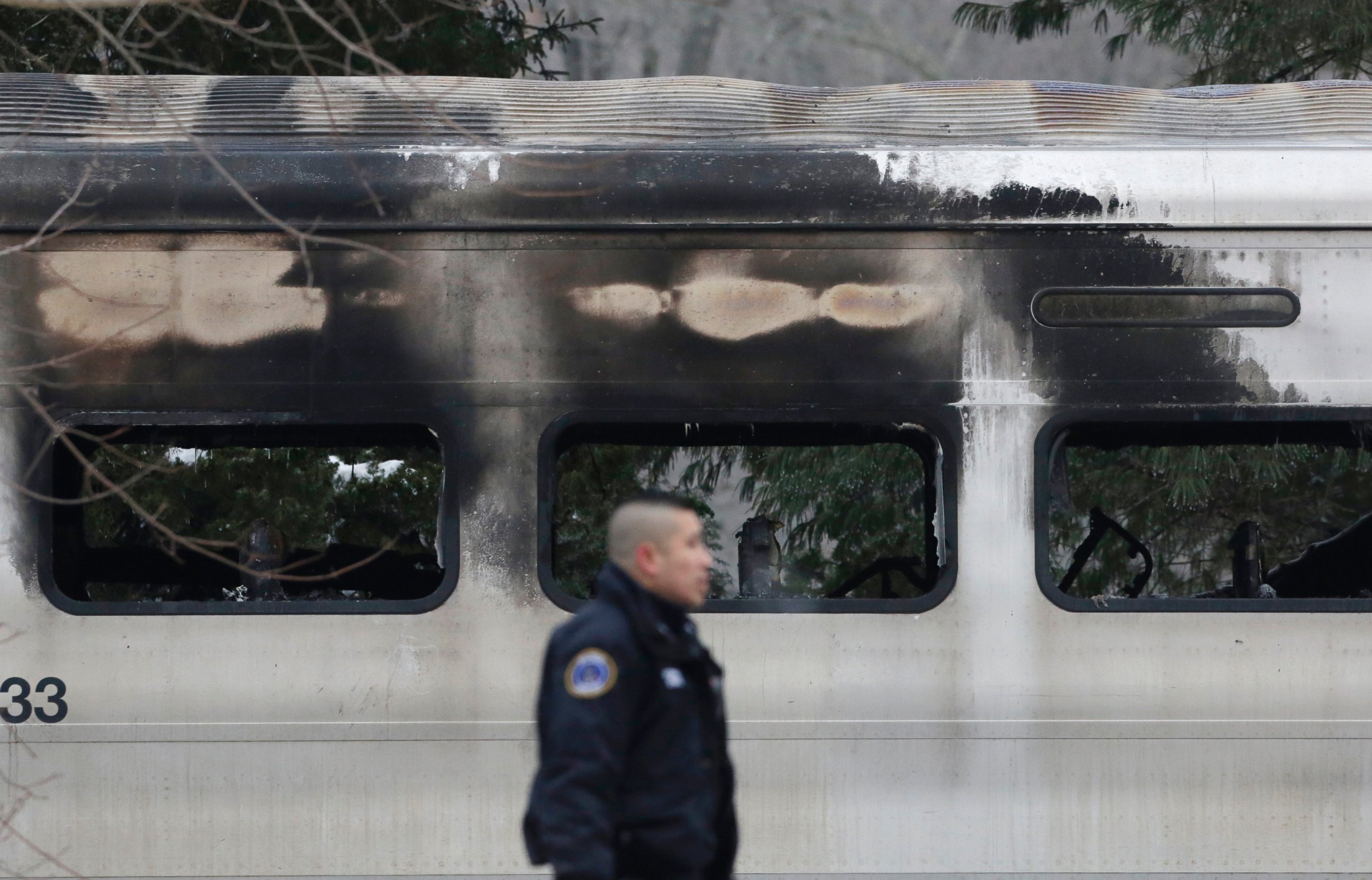 PHOTO: A police officer walks by burned and blackened windows of a Metro-North train stopped on the tracks, on Feb. 4, 2015, in Valhalla, N.Y.