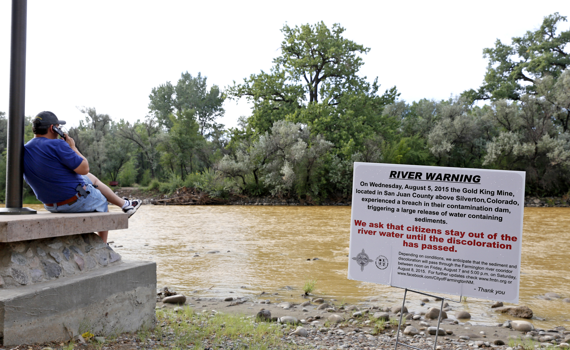 PHOTO: A warning sign from the city is displayed in front of the Animas River as orange sludge from a mine spill upstream flows past Berg Park in Farmington, N.M., Aug. 8, 2015.