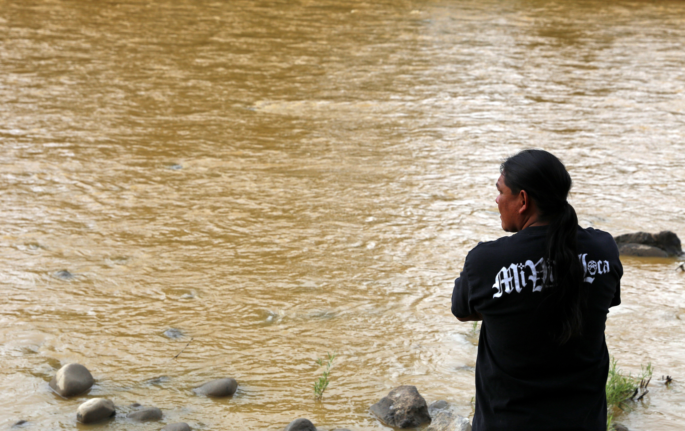 PHOTO: Travis Sells, of Farmington, N.M., looks at the orange sludge from a mine spill upstream flowing past Berg Park in Farmington, Aug. 8, 2015. 