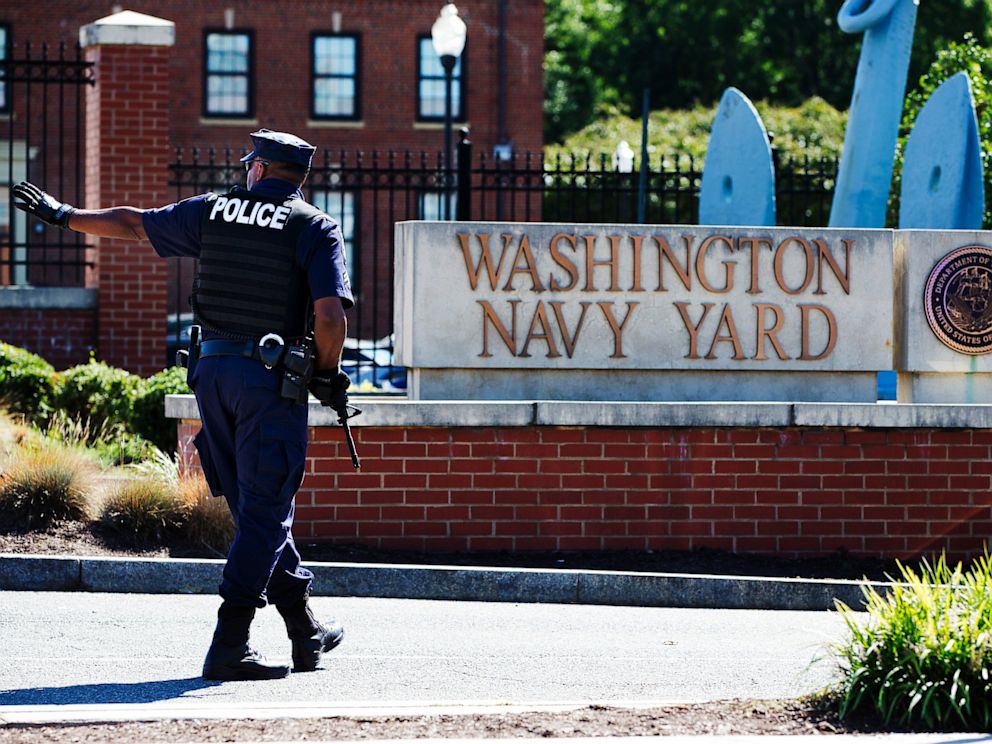 PHOTO: An armed officer who said he is with the Department of Defense, warns a vehicle to stay away from the gate at the Washington Navy Yard in Washington, on Sept. 17, 2013