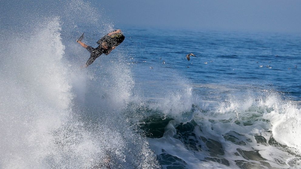 PHOTO: A bogie boarder flies over a wave a surfer rides underneatch a wave at the wedge in Newport Beach, Calif., Aug. 27, 2014.
