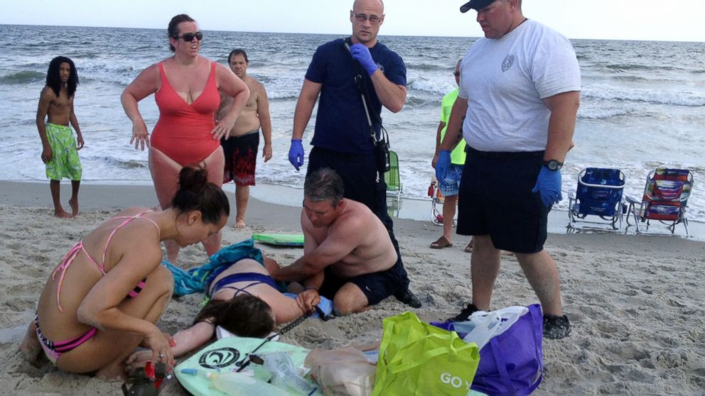 PHOTO: People assist a teenage girl at the scene of a shark attack in Oak Island, N.C., June 14, 2015. 
