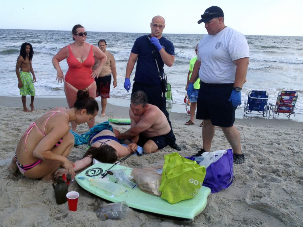 PHOTO: People assist a teenage girl at the scene of a shark attack in Oak Island, N.C., June 14, 2015. 