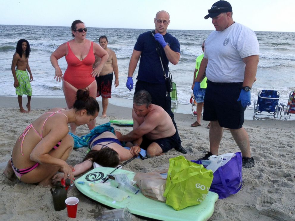 PHOTO: People assist a teenage girl at the scene of a shark attack in Oak Island, N.C., June 14, 2015.