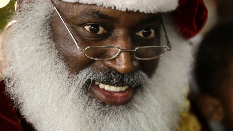In this Dec. 17, 2013 photo, Dee Sinclair, portraying Santa Claus, reads a story to children in Atlanta. "Kids don't see color. They see a fat guy in a red suit giving toys," says Sinclair.