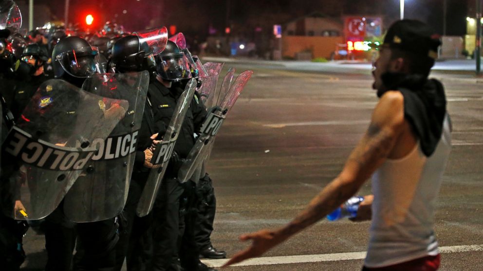 PHOTO: A protester questions police dressed in riot gear as marchers numbering nearly 1,000 take to the streets to protest against the recent fatal shootings of black men by police Friday, July 8, 2016, in Phoenix. 