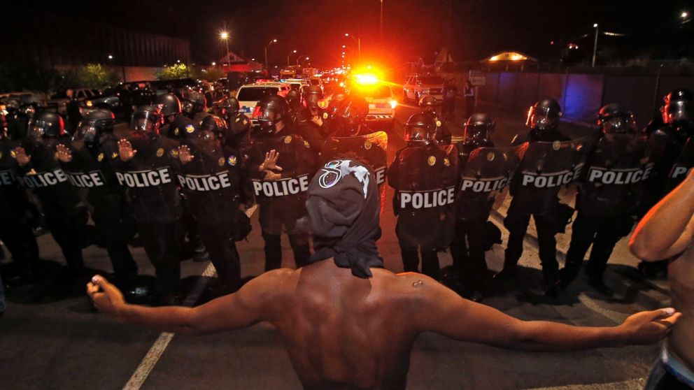 PHOTO: A protester raises him arms in front of a police blockade as marchers take to the streets to demonstrate against the recent fatal shootings of black men by police, Friday, July 8, 2016, in Phoenix. 