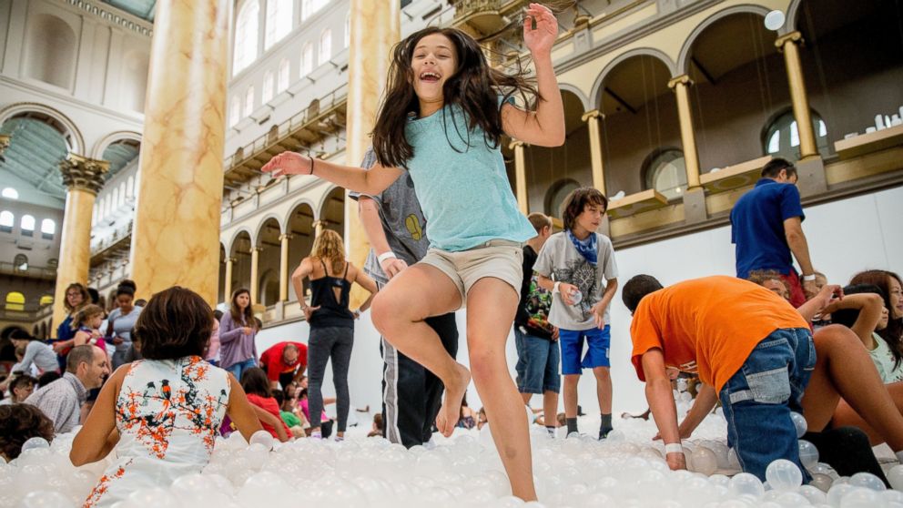 PHOTO: Ilana Cohen, 9, of Alexandria, Va., jumps into a sea of plastic balls at "The Beach", an interactive architectural installation inside the National Building Museum in Washington, July 17, 2015. 