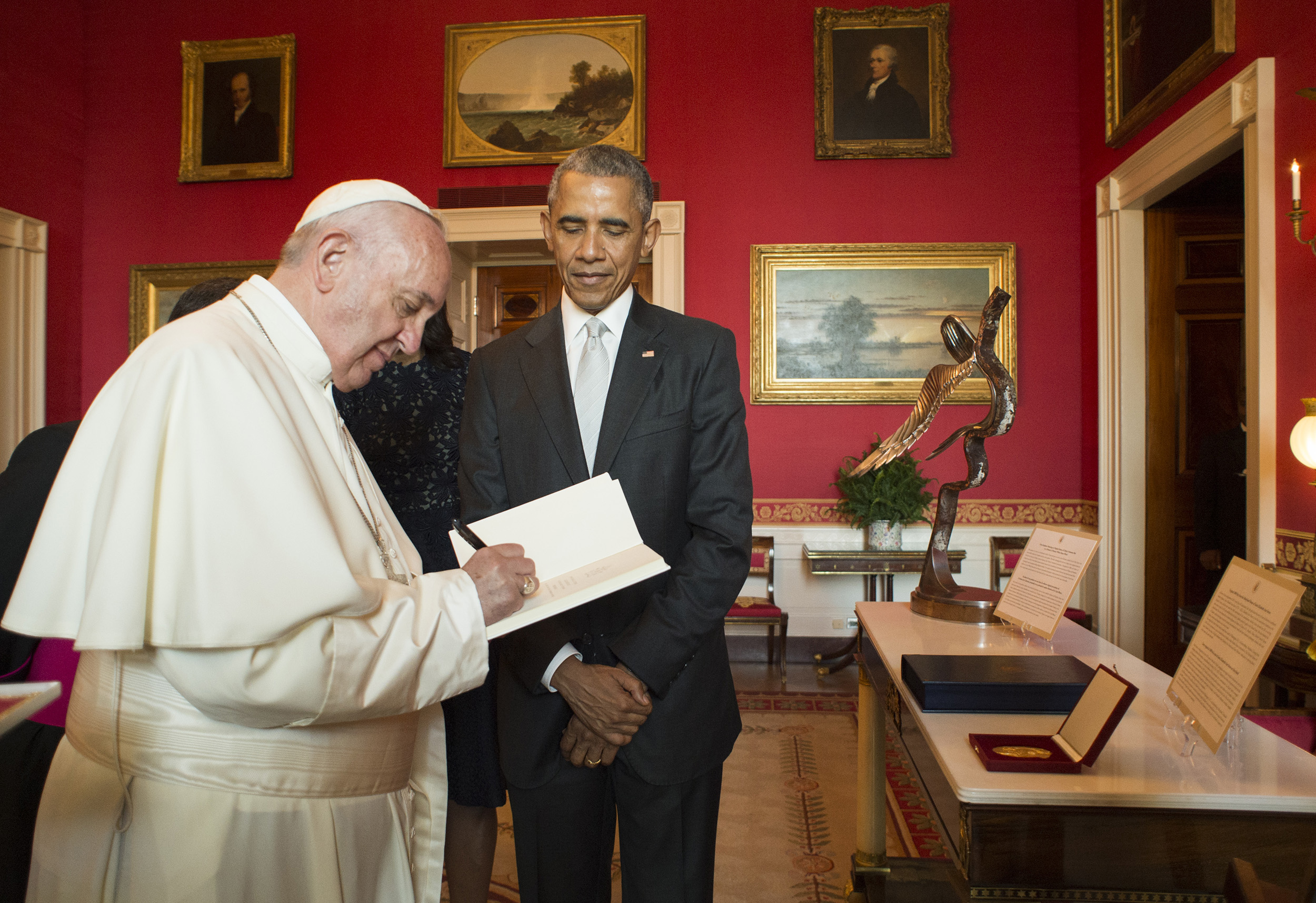 PHOTO: In this photo provided by L'Osservatore Romano, Pope Francis signs a guest book as President Barack Obama looks on at the White House in Washington, Sept. 23, 2015.