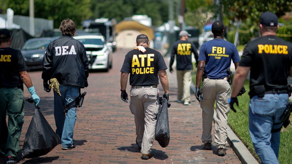 Federal and local law enforcement officials walk through the street next to the scene of a mass shooting at a nightclub, June 13, 2016, in Orlando, Fla.