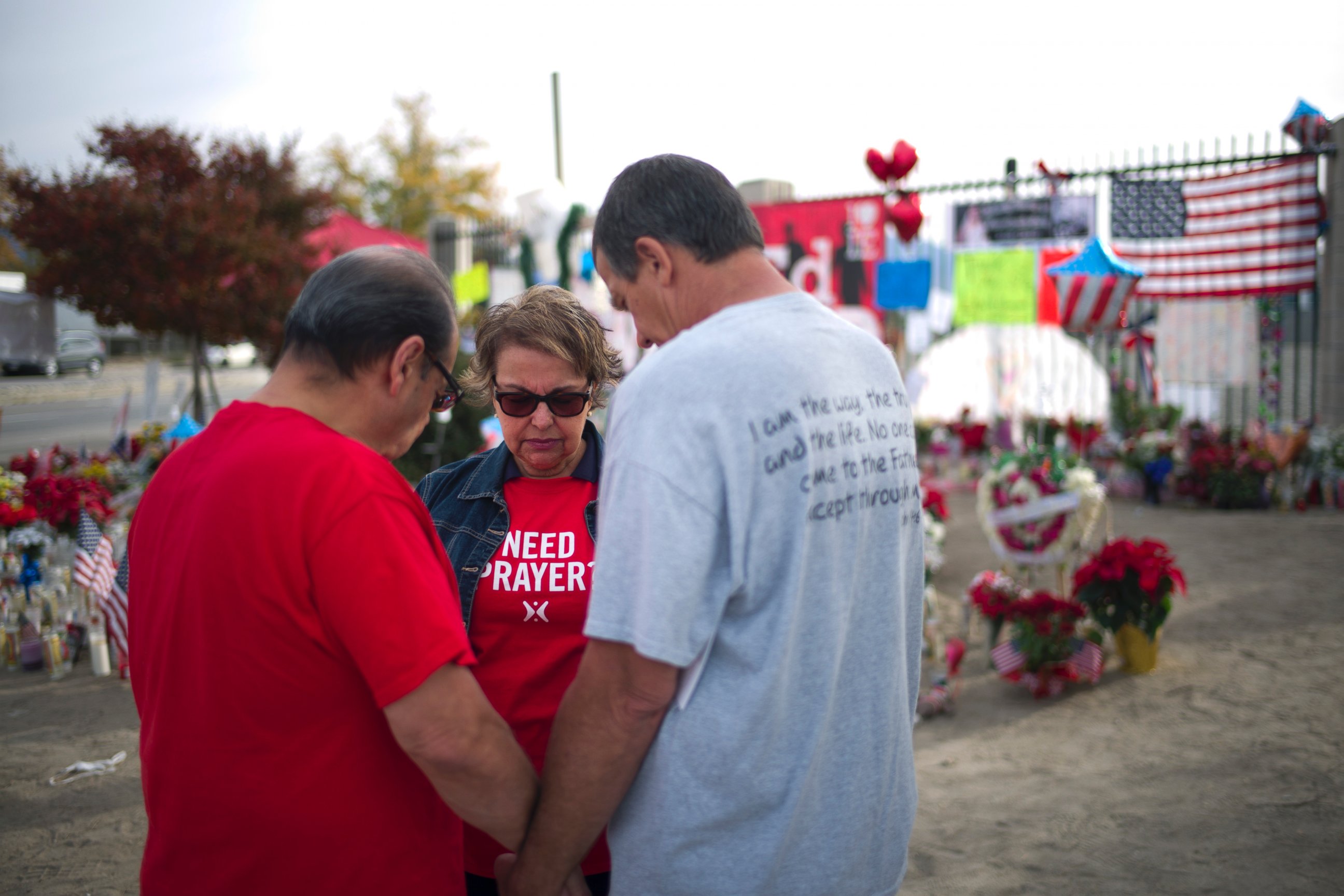 PHOTO: Ray Molina, from left, Molina's wife, Yvonne, and Leonard Lynch pray at a makeshift memorial set up near the Inland Regional Center, the site of a fatal shooting that killed 14 people, Dec. 9, 2015, in San Bernardino, Calif.