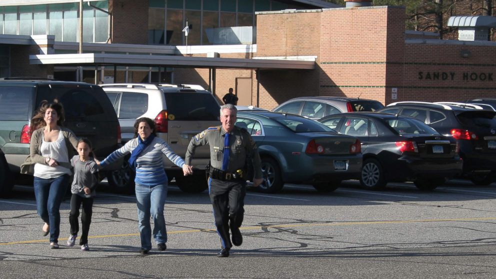 A police officer leads two women and a child from Sandy Hook Elementary School in Newtown, Conn., in this Dec. 14, 2012 photo.