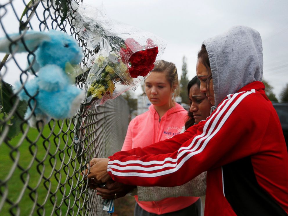 PHOTO: Student Tyanna Davis, right, places flowers on the fence bordering Marysville-Pilchuck High School in Marysville, Wash., Oct. 25, 2014.