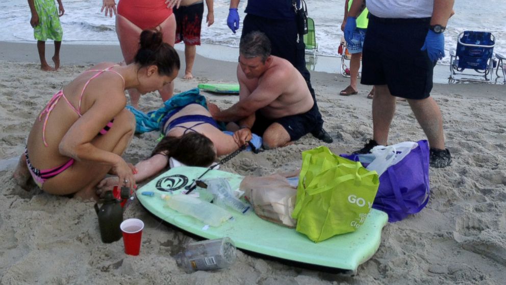 People assist a teenage girl at the scene of a shark attack in Oak Island, N.C., Sunday, June 14, 2015.