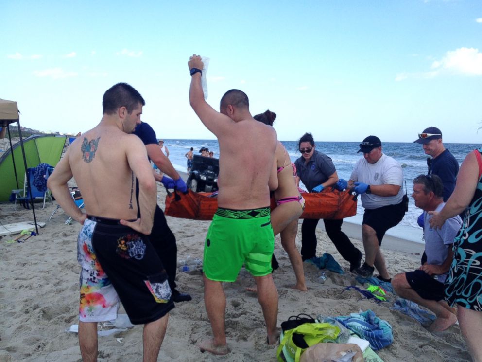 PHOTO: Emergency responders assist a teenage girl at the scene of a shark attack in Oak Island, N.C., June 14, 2015. 