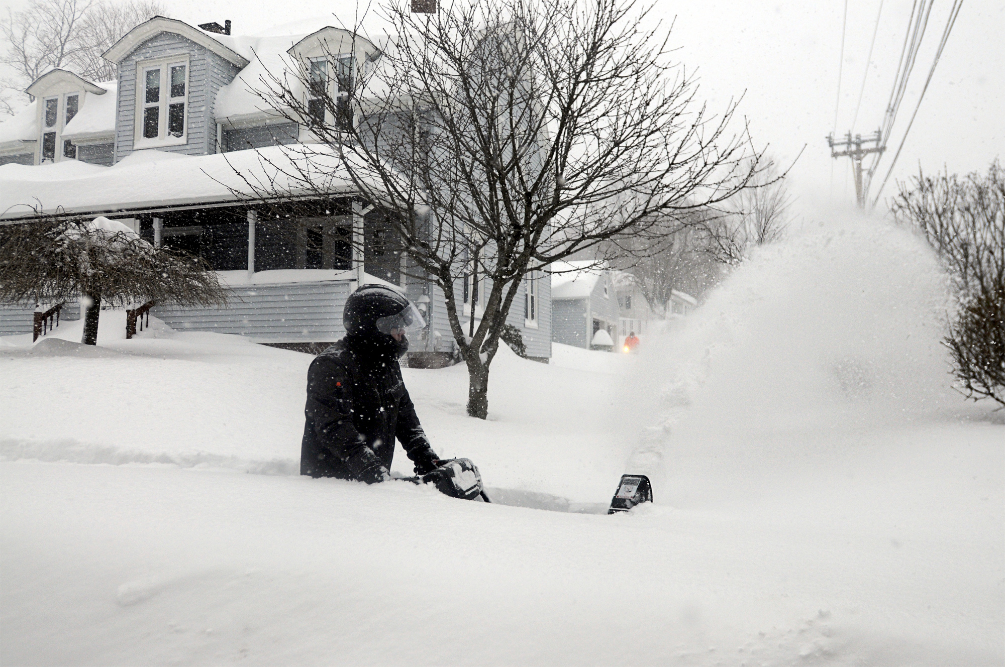 PHOTO: John Slasell wades through waist-deep snow as he snow blows the sidewalk along Slater St. in Webster, Mass. 