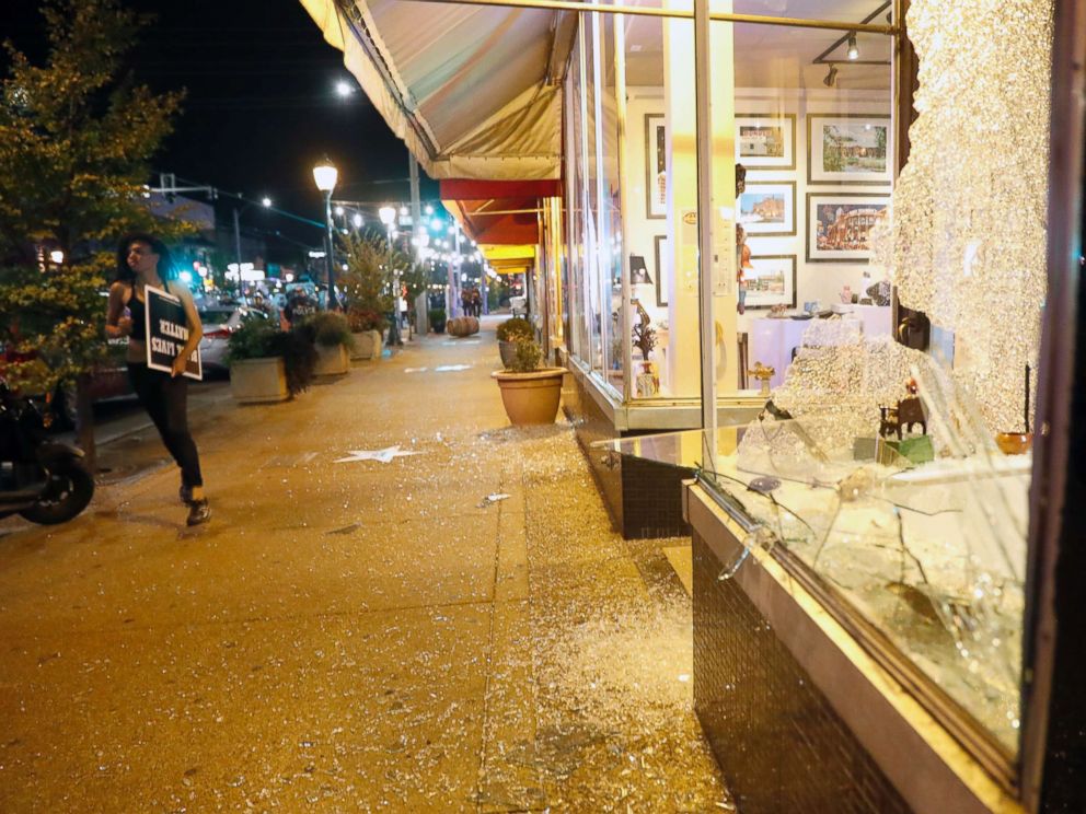 PHOTO: A woman runs past a broken window as police try to clear a violent crowd Saturday, Sept. 16, 2017, in University City, Mo.