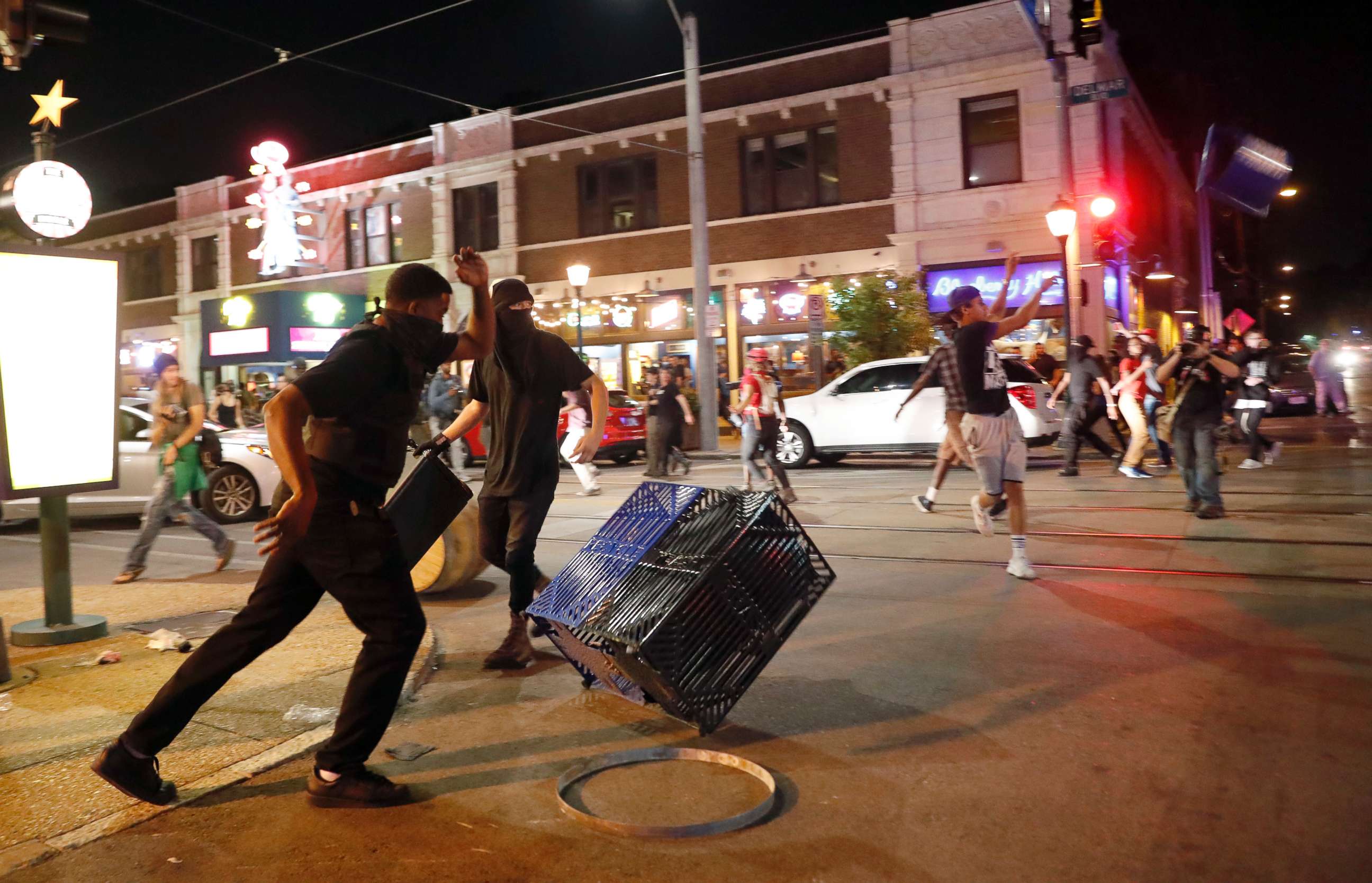 PHOTO: People overturn trash cans and throw objects as police try to clear a violent crowd Saturday, Sept. 16, 2017, in University City, Mo. 