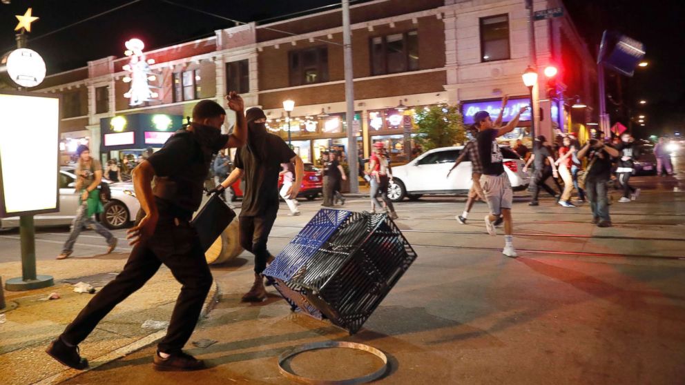 PHOTO: People overturn trash cans and throw objects as police try to clear a violent crowd Saturday, Sept. 16, 2017, in University City, Mo. 