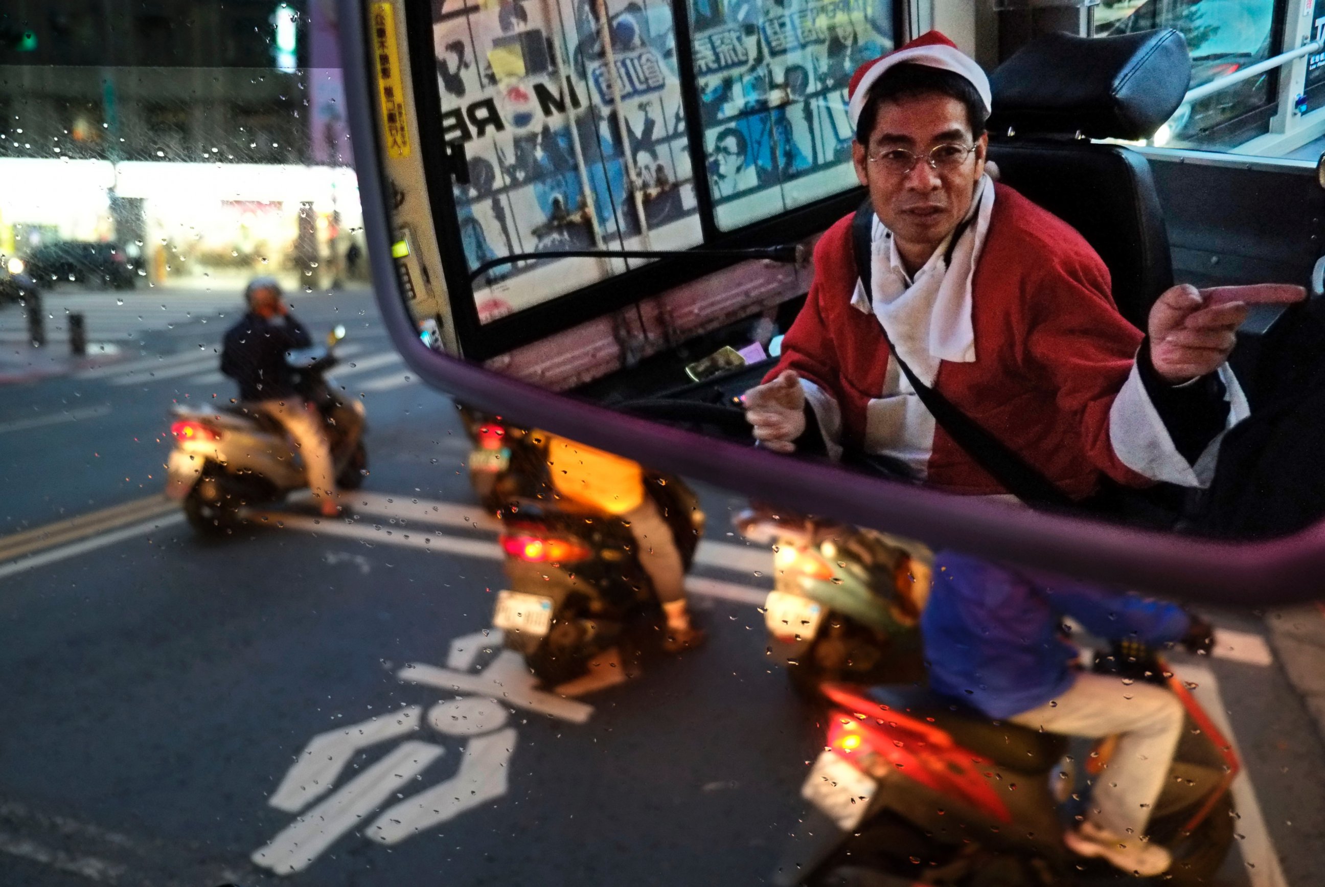 PHOTO: Reflected in a mirror, a public bus driver dressed as Santa Claus gives a passenger directions on Dec. 18, 2013, in Taipei, Taiwan.