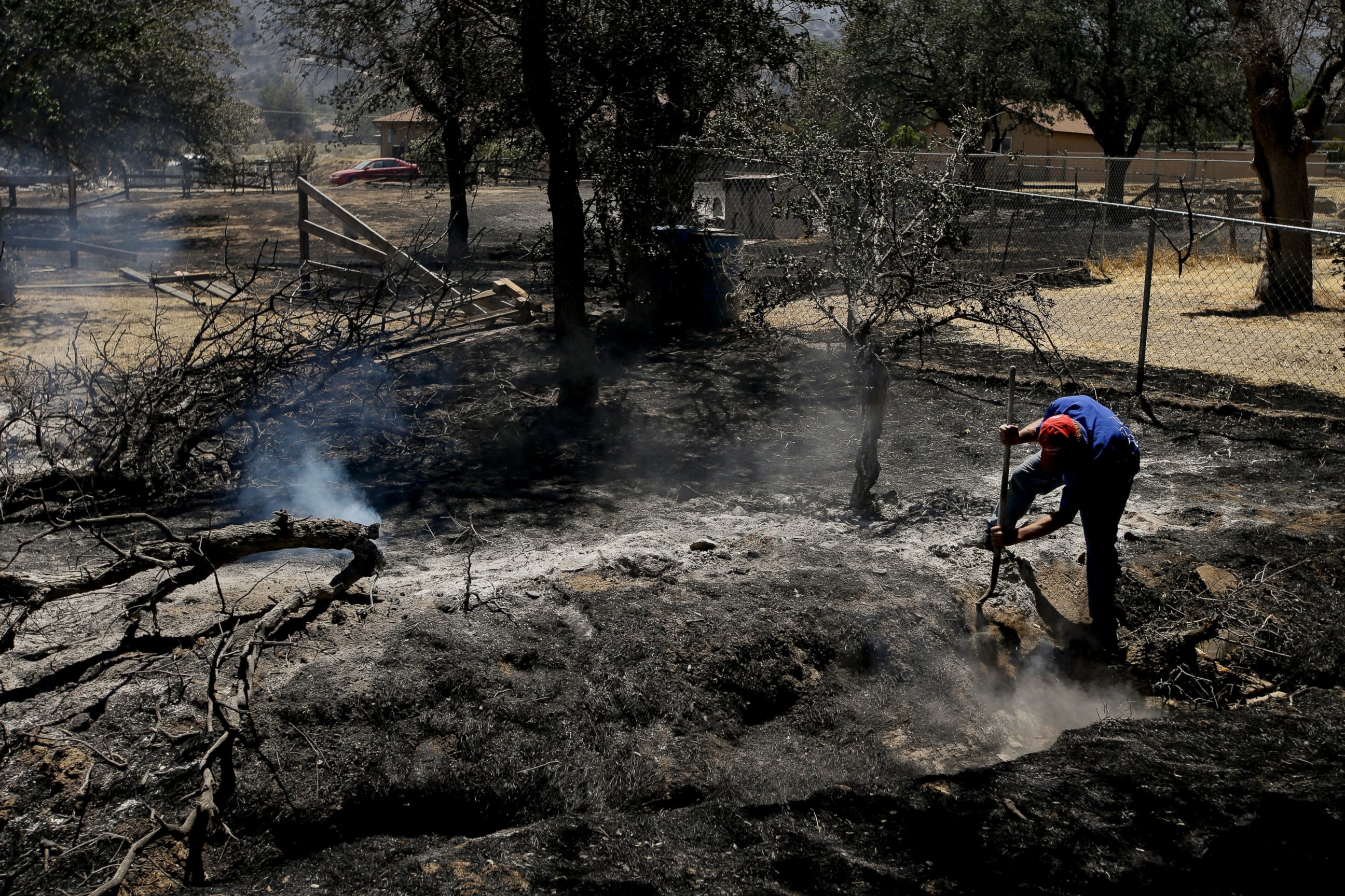PHOTO: Alan Germain puts out hotspots on his neighbor's property destroyed by a wildfire, June 24, 2016, near Lake Isabella, Calif.