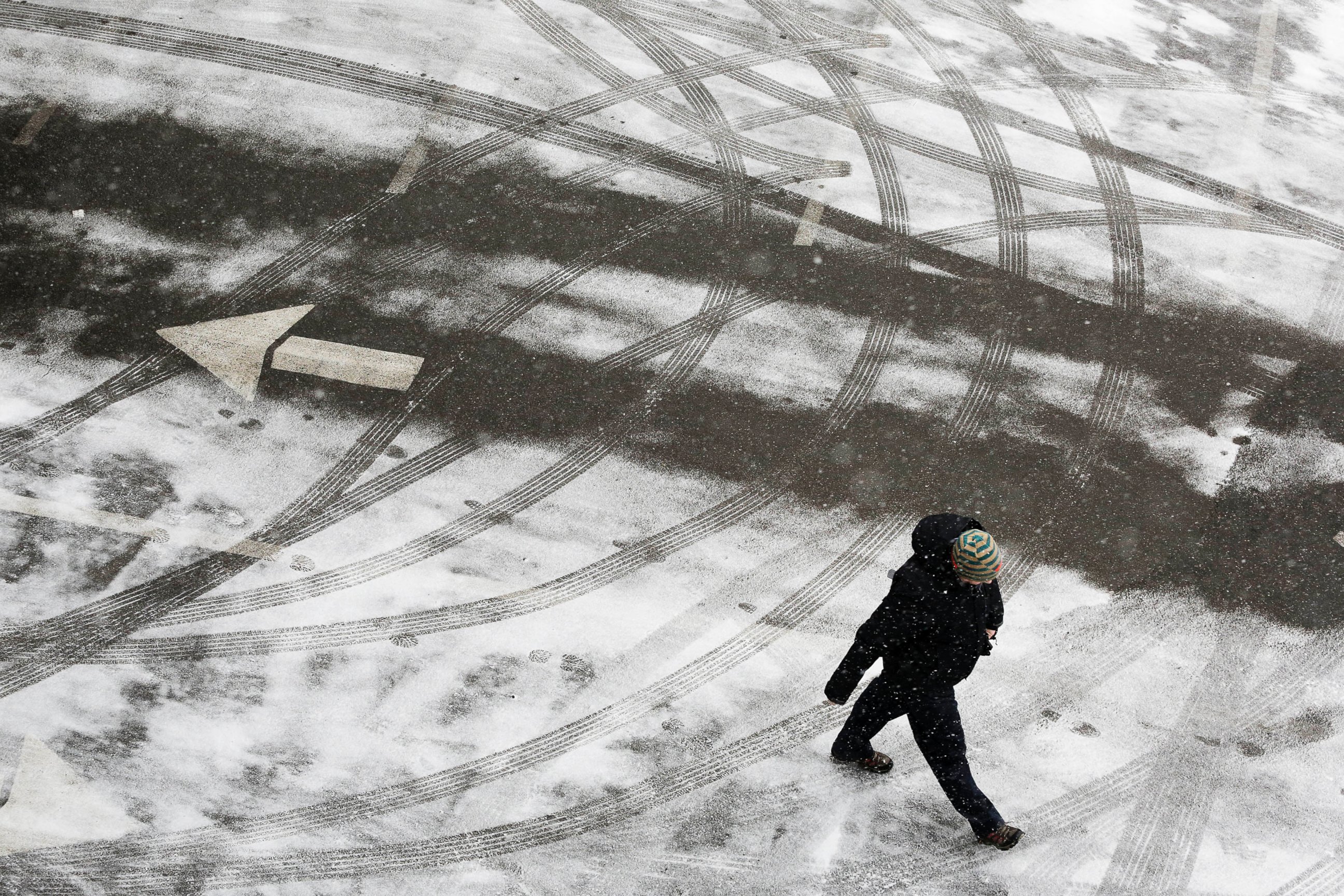 PHOTO: A pedestrian crosses a snowy parking lot before heavy snowfall arrives, Jan. 26, 2015, in New York. 