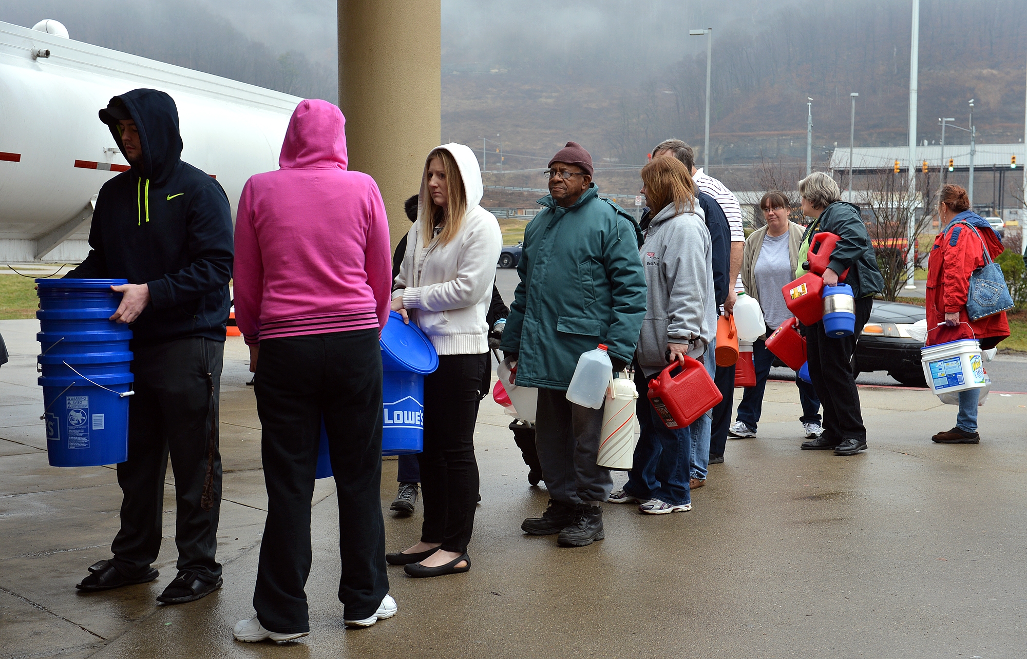 PHOTO: People wait in line for water from a 7500 gallon tanker truck brought in from Washington, Pa., on Jan. 10, 2014, at Riverside High School near Charleston, W.Va. 
