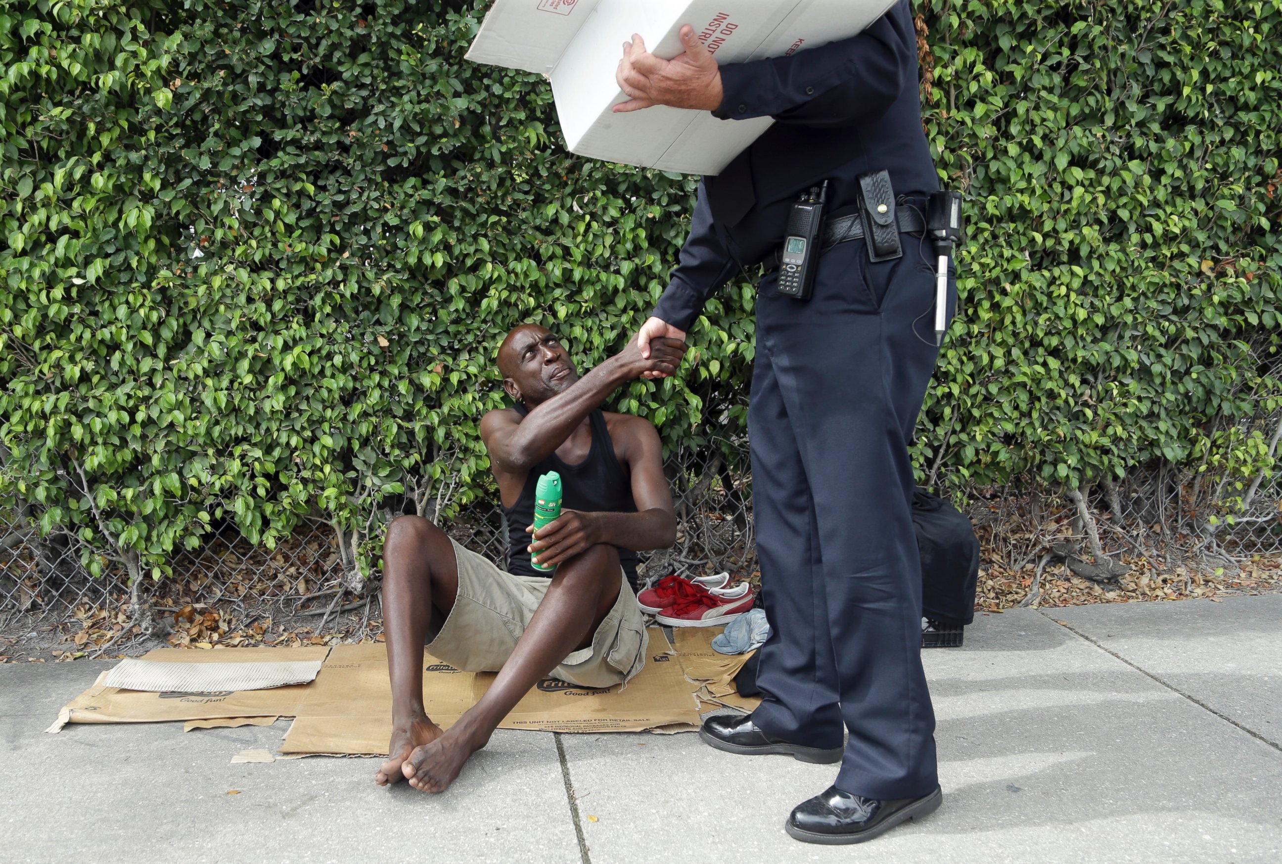 PHOTO: Lorenzo Ward, 45, who is homeless, shakes hands with Miami police officer James Bernat, after Bernat gave him a can of insect repellent, Aug. 2, 2016 in the Wynwood neighborhood of Miami.
