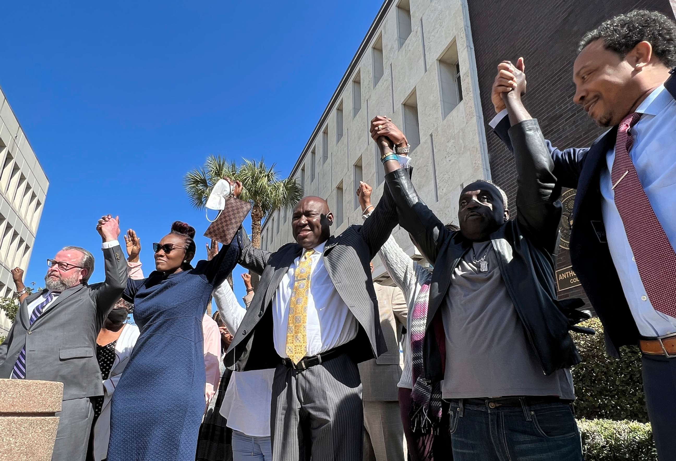 PHOTO: The family and attorneys of the Ahmaud Aubery raise their arms in victory after all three men were found guilty of hates crimes at the federal courthouse in Brunswick, Ga., Feb. 22, 2022.