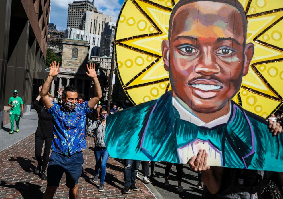 PHOTO: Mural artist David Fichter holds his painting of Ahmaud Arbery  while participating in a protest and march organized by Beyond New Perspectives marches in Boston, June 13, 2020. 