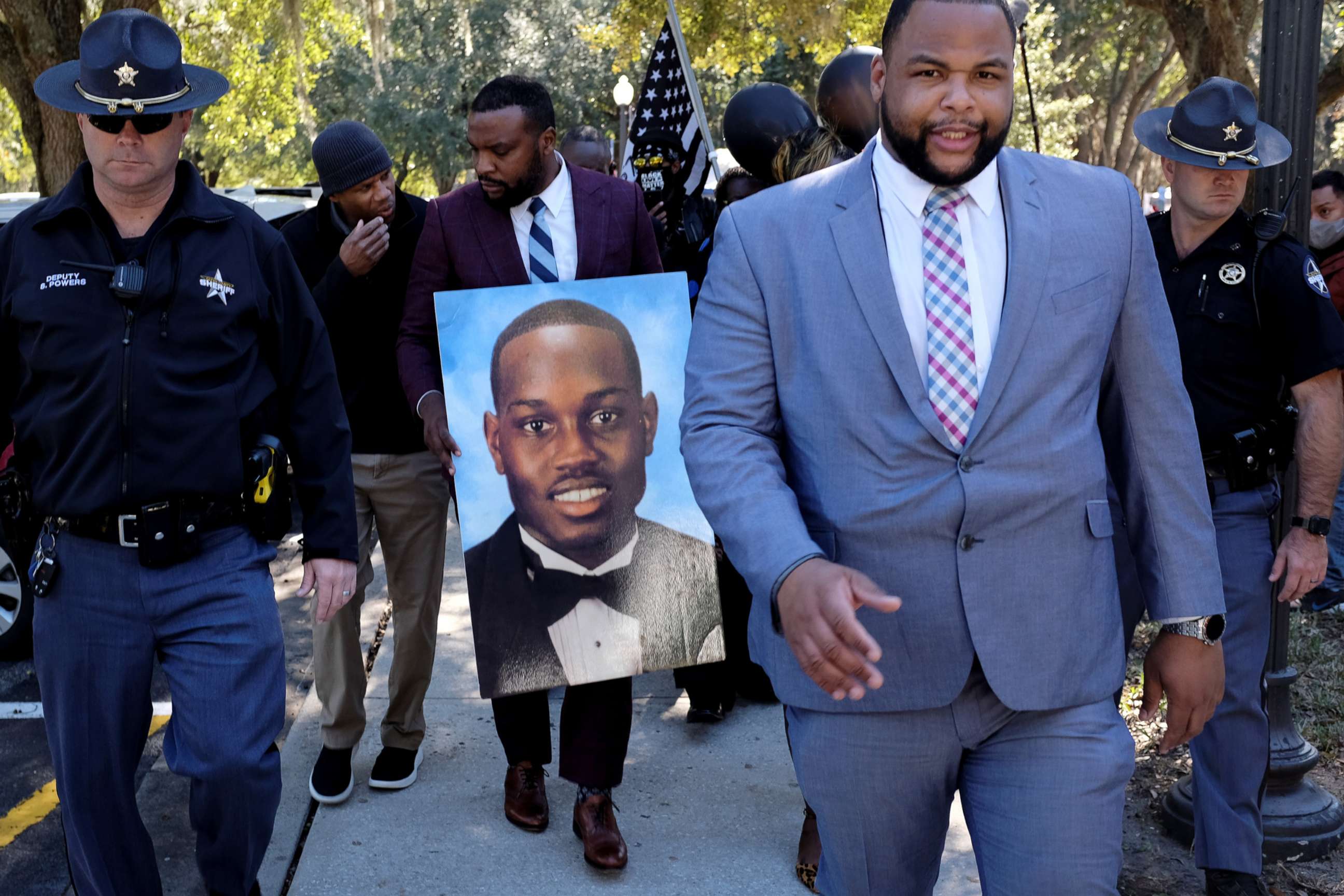 PHOTO: Attorney Lee Merritt holds a poster depicting Ahmaud Arbery as he leaves the courthouse as jury begins deliberating whether Greg McMichael, Travis McMichael and William "Roddie" Bryan murdered Ahmaud Arbery, in Brunswick, Ga., Nov. 23, 2021.