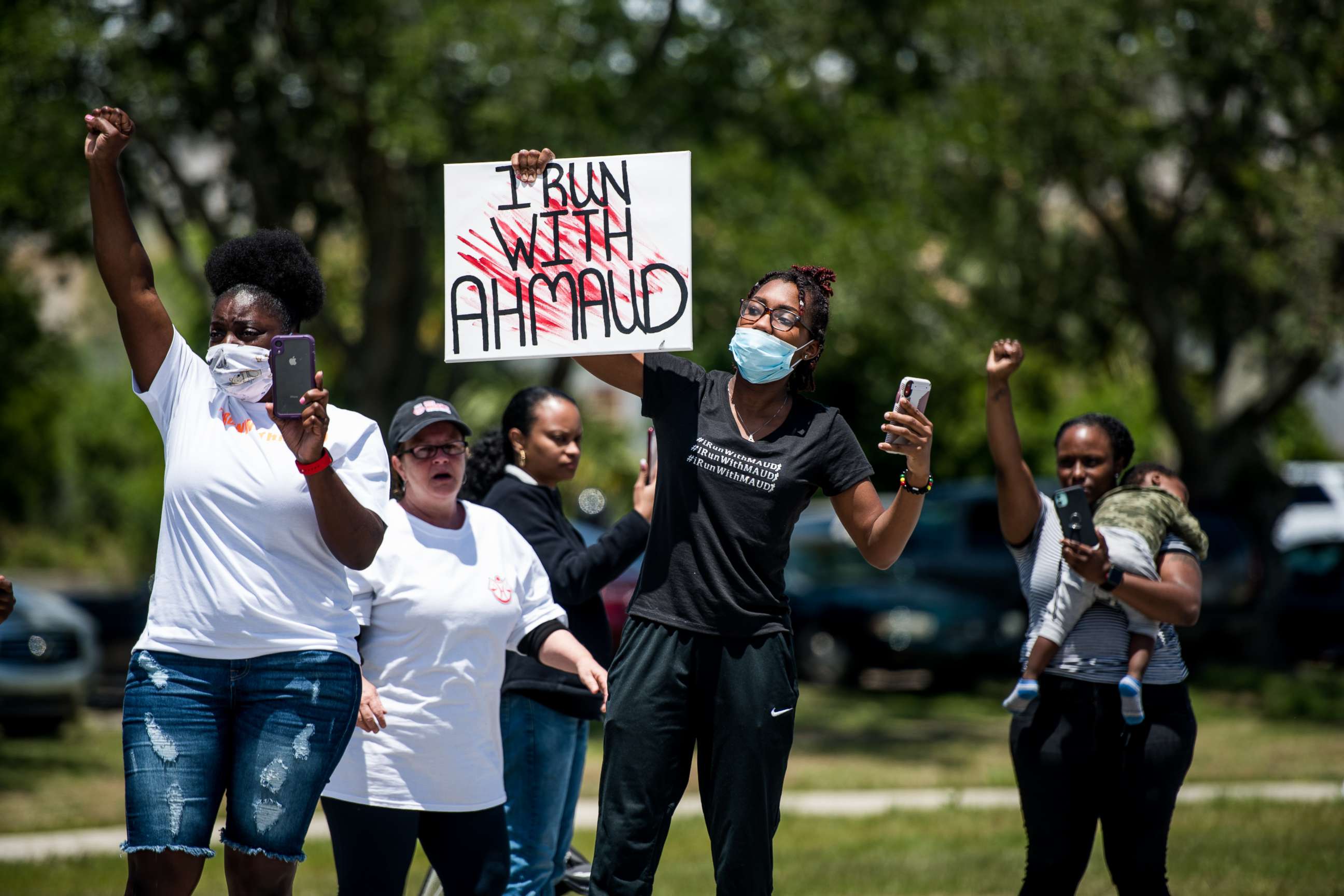 PHOTO: Demonstrators raise their fists at a parade of passing motorcyclists riding in honor of Ahmaud Arbery at Sidney Lanier Park on May 9, 2020 in Brunswick, Ga. 
