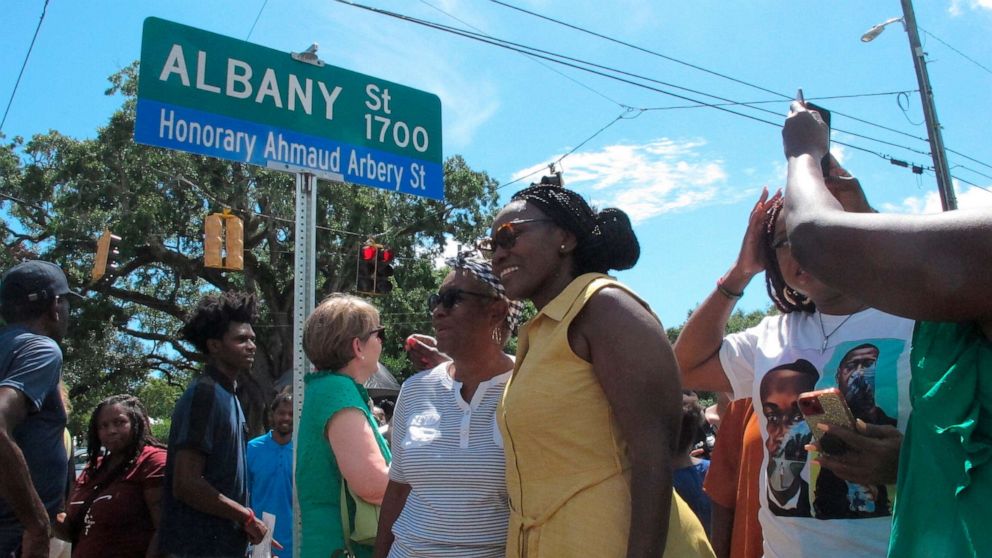 PHOTO: Wanda Cooper-Jones poses for photos with supporters beneath a new street sign honoring her son, Ahmaud Arbery, that was unveiled, Aug. 9, 2022, in Brunswick, Ga. 