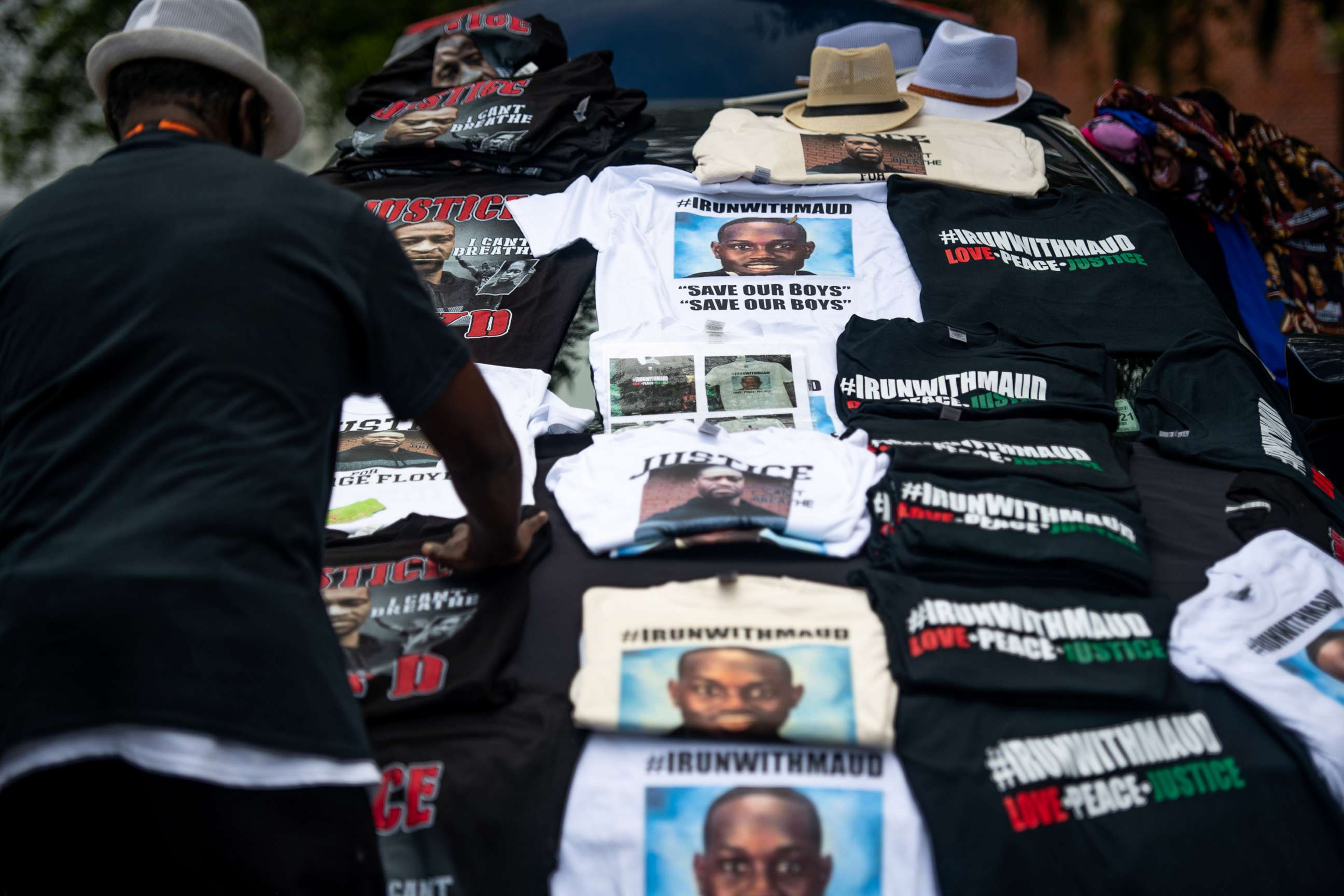 PHOTO: A man organizes t-shirts memorializing George Floyd and Ahmaud Arbery outside the Glynn County Courthouse where Gregory and Travis McMichael attended a preliminary hearing on June 4, 2020 in Brunswick, Ga.