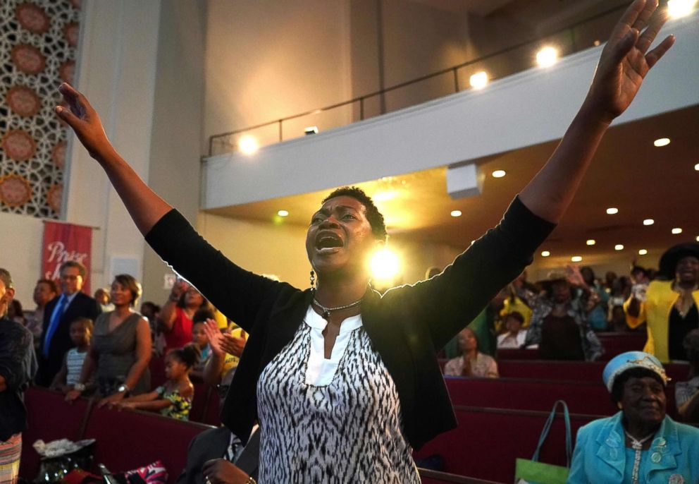 PHOTO: Avis Doughton holds her arms up as the Rev. Jesse Jackson speaks celebrating the life of singer Aretha Franklin at her father's church, New Bethel Baptist, during a Sunday morning service in Detroit, August 19, 2018.