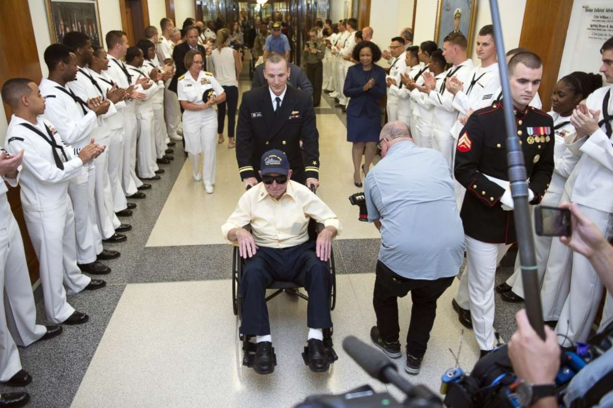 PHOTO: Service members applaud USS Arizona survivor Navy Coxswain Howard Kenton Potts, seated, as he passes through a Pentagon hallway in Arlington, Va. July 17, 2017. The Arizona was attacked at Pearl Harbor at the beginning of World War II. 