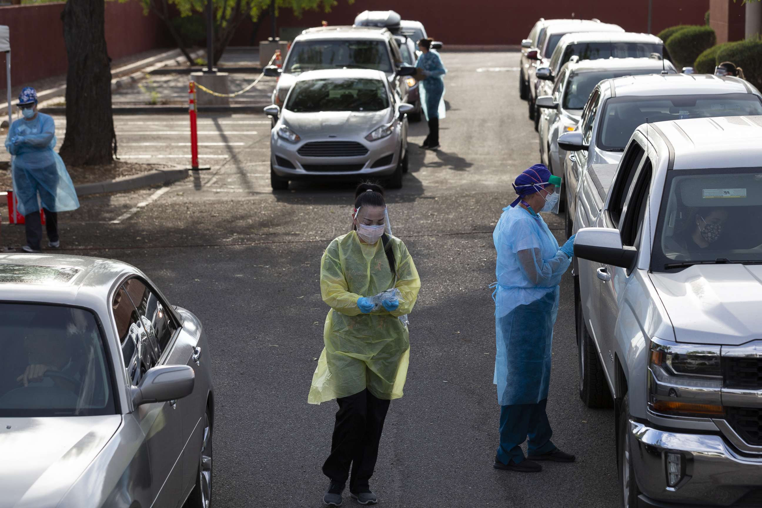 PHOTO: Healthcare workers wearing personal protective equipment (PPE) administer tests at an El Rio Health Covid-19 drive-thru testing site in Tucson, Ariz., July 13, 2020.