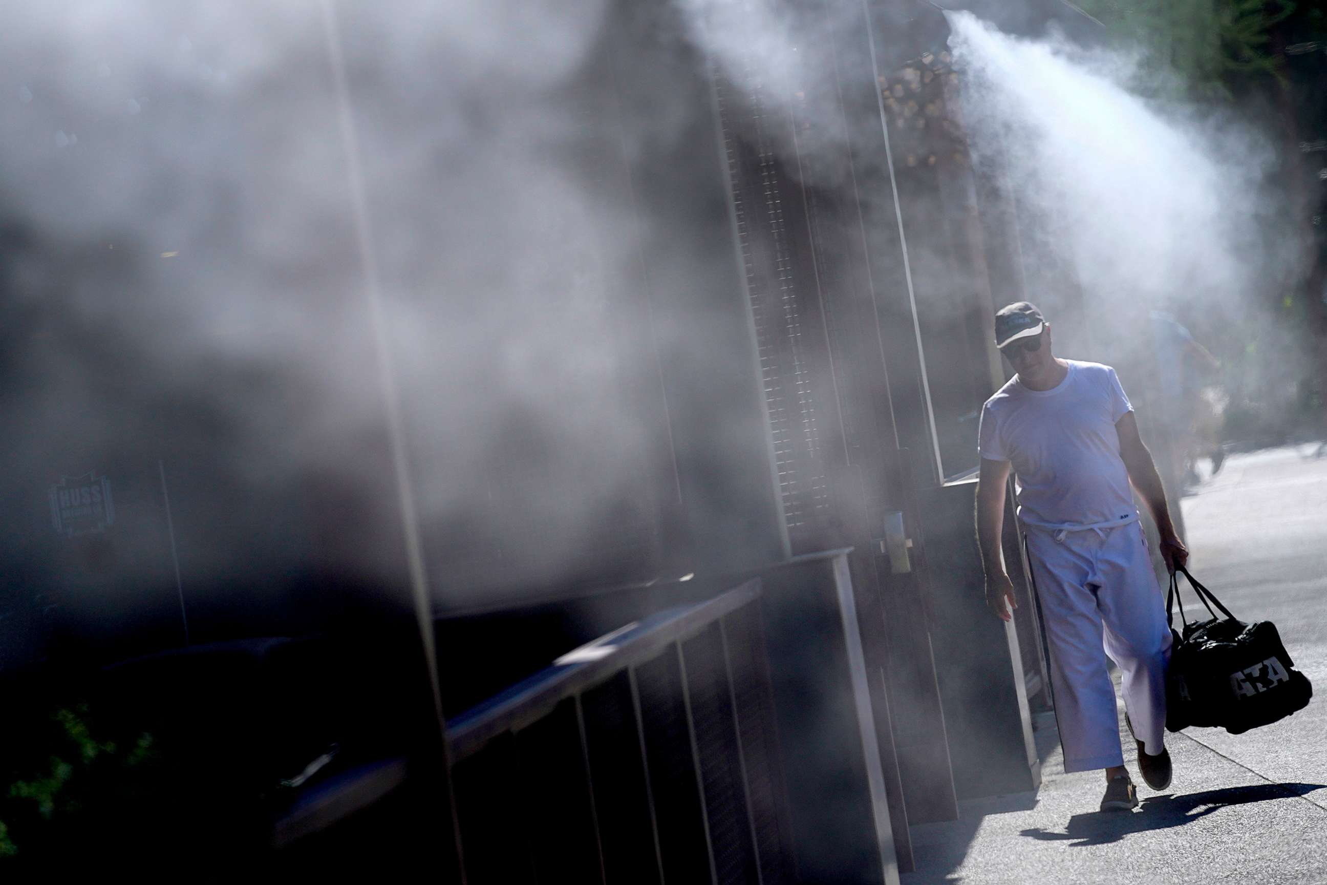 PHOTO: A man walks along a sidewalk under the misters, on July 14, 2023, in downtown Phoenix.