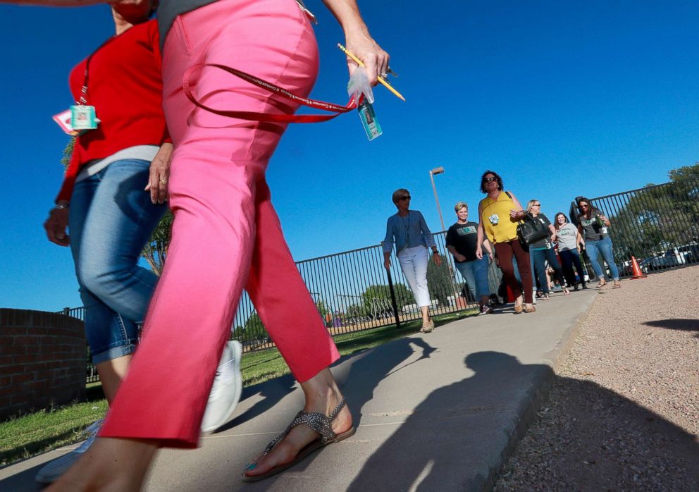 PHOTO: Teachers walk in together as they arrive for work at San Marcos Elementary School, May 4, 2018, in Chandler, Ariz., after a statewide teachers strike ended.