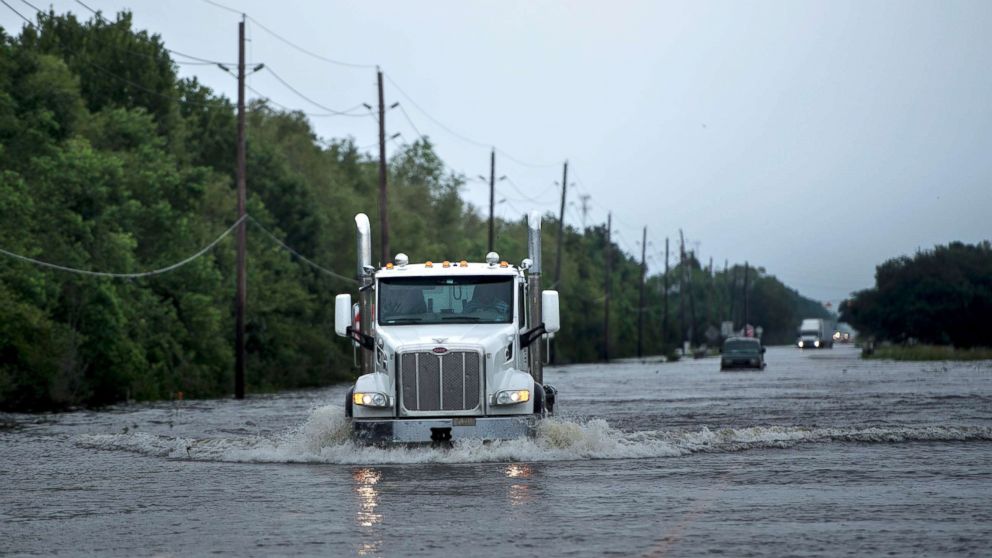PHOTO: Trucks make their way through flood waters on a main road leading to the Arkema Inc. chemical plant that was in crisis during the aftermath of Hurricane Harvey, Aug. 30, 2017, in Crosby, Texas.