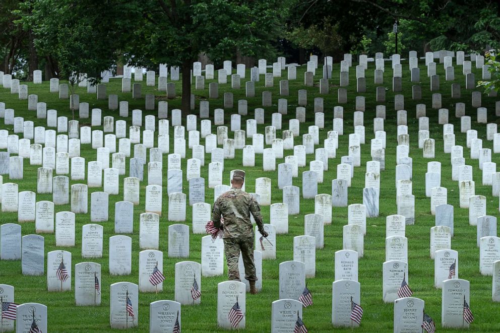 PHOTO: A member of the 3rd U.S. Infantry Regiment places flags at the headstones of U.S. military personnel buried at Arlington National Cemetery, in preparation for Memorial Day, on May 26, 2022, in Arlington, Va.